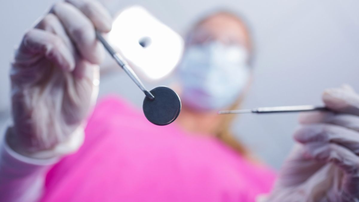 A person in a pink shirt holds dental tools and promotes dental care at Smiles Dentistry in Atlantis, FL.