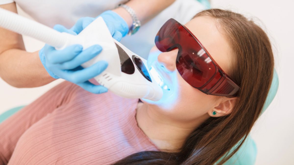 A woman undergoing a teeth whitening procedure at a dental clinic.