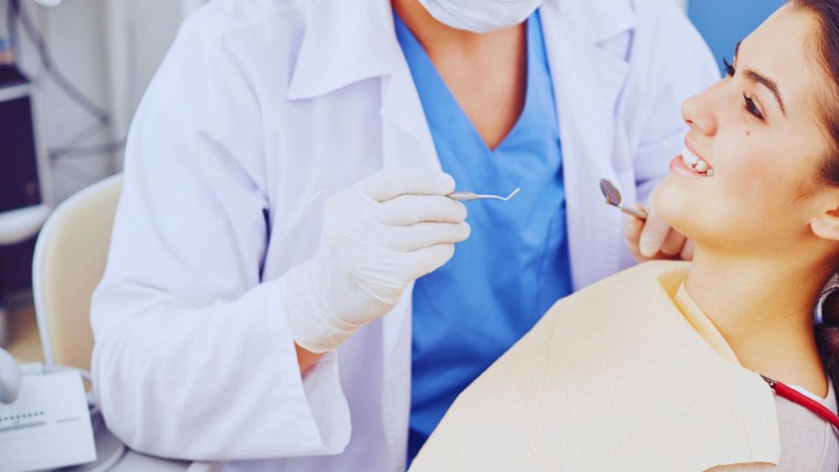 A woman undergoing a dental examination by a dentist in a clinical setting, focusing on her oral health.