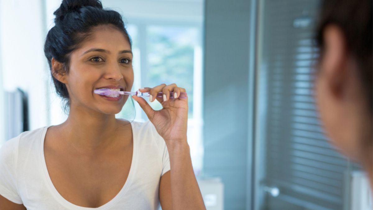 A woman brushes her teeth before going to her dental appointment.