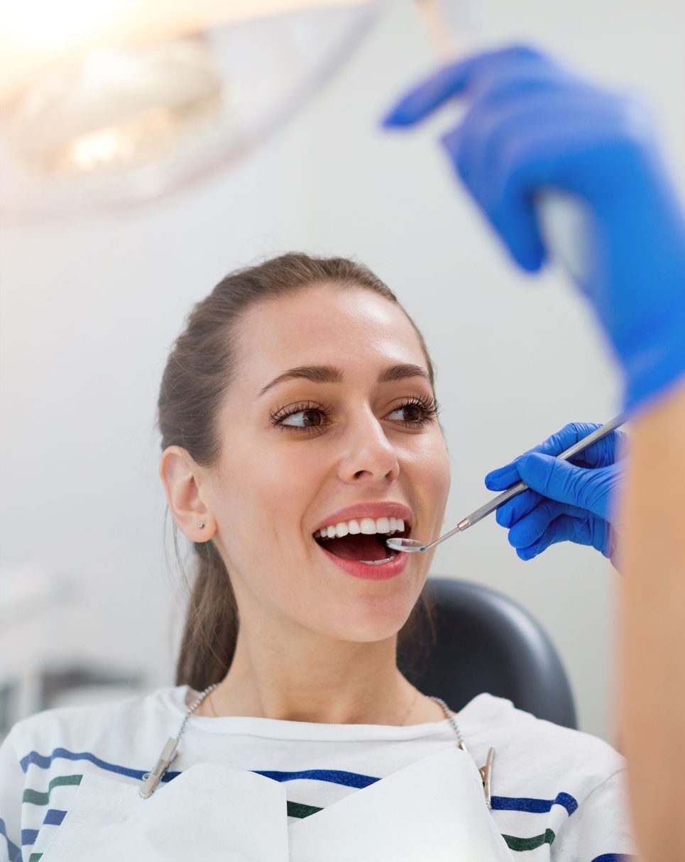 A woman is having her teeth professionally cleaned by a dentist in a bright dental clinic.