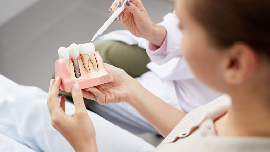 A woman holds a tooth model in her hand, demonstrating dental anatomy and oral health education.
