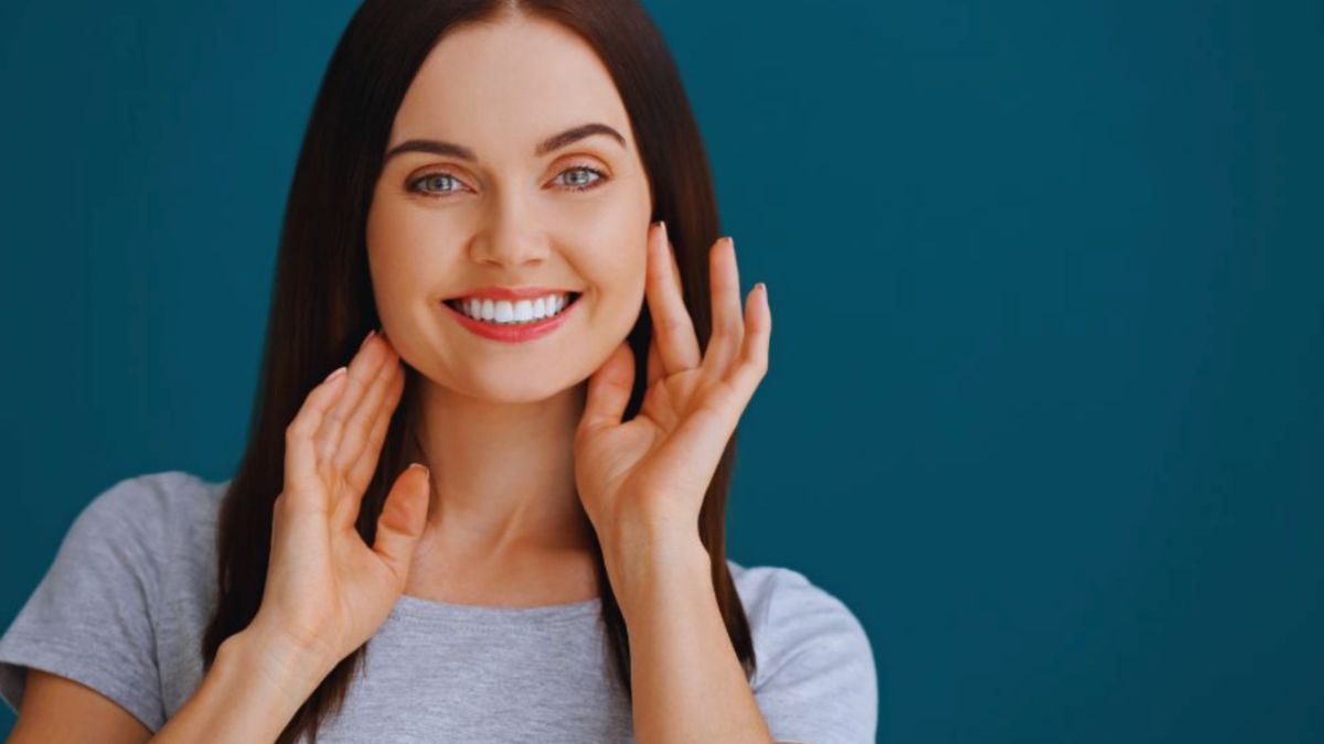 Smiling woman with an attractive smile, hands on her face, exuding joy and warmth.
