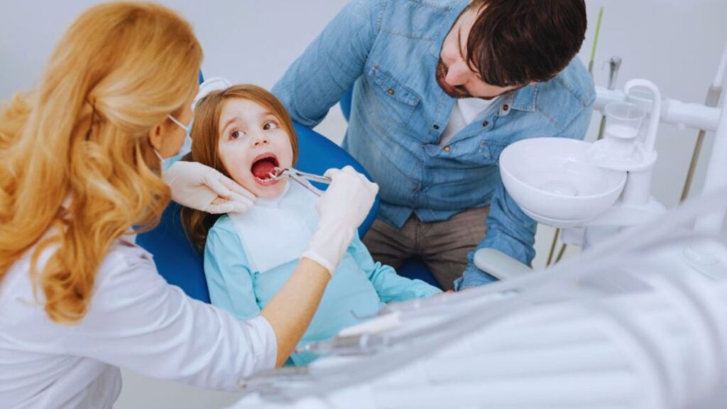 A pediatric dentist examines a young girl’s teeth in a dental office in Lake Worth Beach.