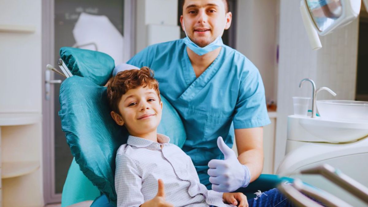 A pediatric dentist and a young boy show a thumbs-up, creating a friendly atmosphere in Lake Worth Beach.